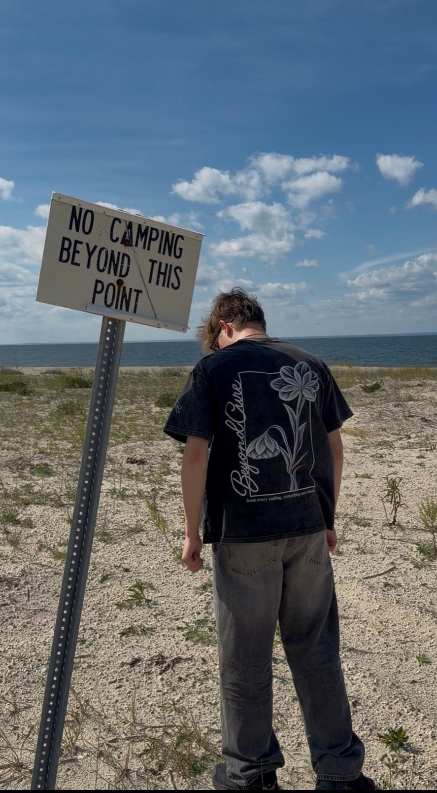 BeyondCure beach campaign back graphic beside the Beyond This Point sign